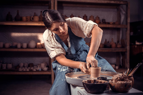 Γοητευτική θηλυκό πλοίαρχος αποδεικνύει τη διαδικασία της παραγωγής κεραμικά πιάτα χρησιμοποιώντας την παλιά τεχνολογία. Βιοτεχνία. - Φωτογραφία, εικόνα