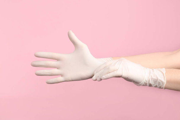 Person putting on medical gloves against pink background, closeup of hands - Foto, afbeelding