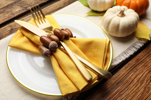 Nastavení podzimního stolu s dýněmi a žaludy na dřevěném pozadí, detailní záběr - Fotografie, Obrázek