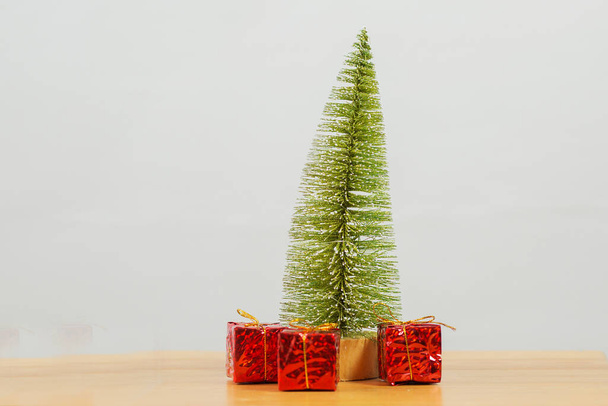 Christbaumständer mit drei roten Weihnachtsgeschenken auf grauem Hintergrund - Foto, Bild