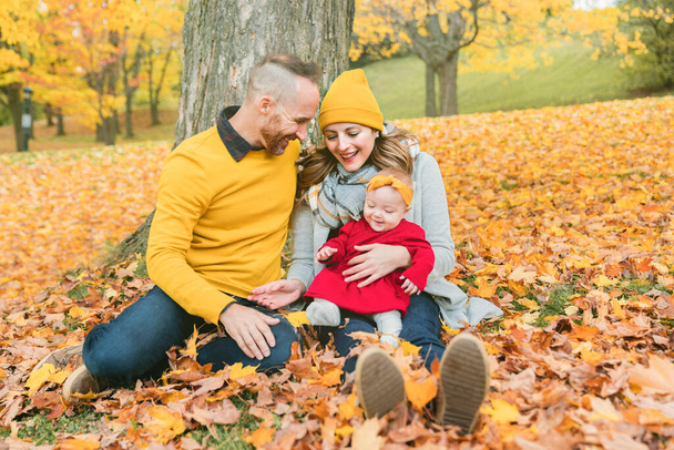 Baby daughter and her parents in the autumn season in park - 写真・画像
