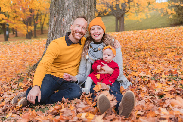 Baby daughter and her parents in the autumn season in park - Φωτογραφία, εικόνα