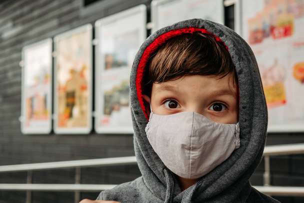Un niño con una máscara protectora entra en el supermercado. Proteger a un niño del coronavirus covid-19 en un supermercado. - Foto, Imagen