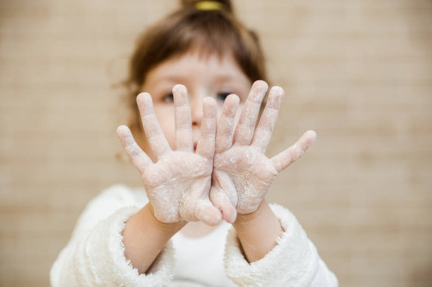 Brunette baby girl is preparing in kitchen. Funny little girl is covered in flour.Children chef concept.Close up - Fotoğraf, Görsel