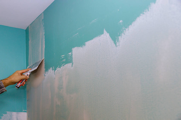 Réparation murale dans son propre appartement mastic blanc de mur mettant du plâtre sur le mur avec spatule - Photo, image