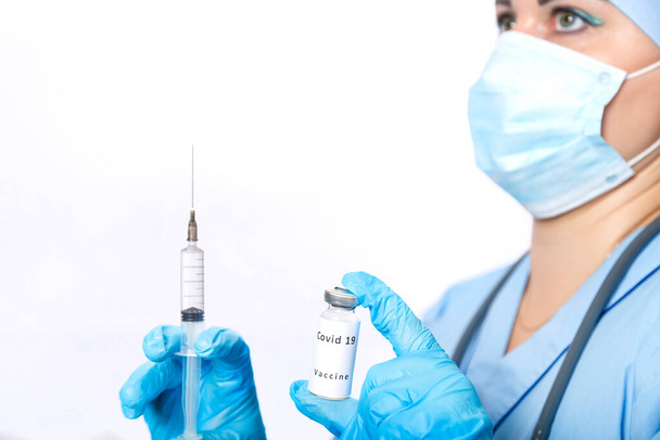 A vial with a vaccine against the virus and a syringe in the hands of a masked doctor. - Fotoğraf, Görsel
