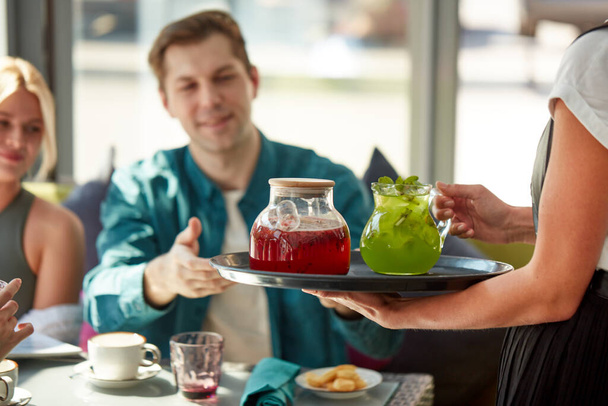 pleasant waiter give beverages on tray to customers - Zdjęcie, obraz