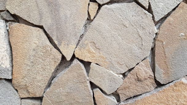 Stenen stukken mozaïek muur achtergrond. Ruwe stenen textuur achtergrond. Een metselwerk achtergrond. Stenen metselwerk wand oppervlak close-up - Foto, afbeelding