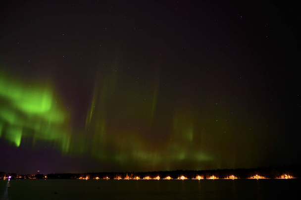 Vue du paysage de Aurora borealis faisceau vert de aurores boréales avec queue violette à côté d'un lac sous un ciel étoilé avec réflexion dans le pays scandinave - Photo, image