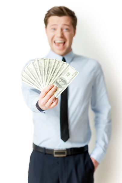 Man in formalwear holding money outstretched and expressing positivity - 写真・画像