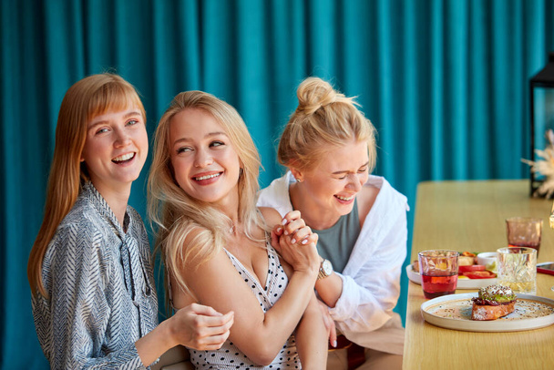girlfriends laugh, have fun while sitting in restaurant - Foto, Imagen
