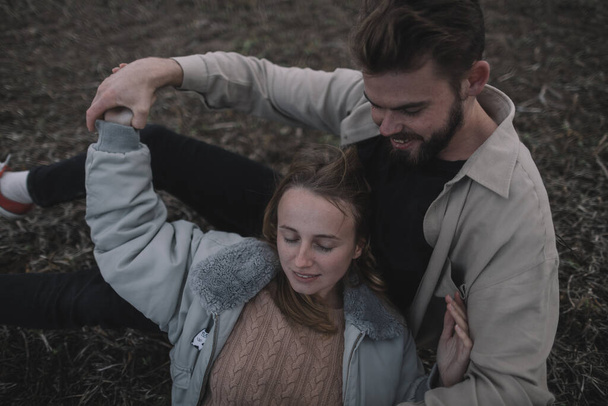 una coppia innamorata cammina in un campo di soia aperto la sera con tempo nuvoloso e abbraccia molto - Foto, immagini