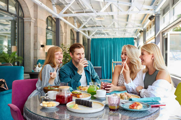 cheerful caucasian friends spending time together in bright cozy time cafe - Фото, зображення