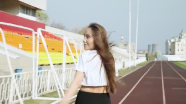 Foto de seguimiento de un joven corredor de fitness en ropa deportiva corriendo en pista de estadio - Imágenes, Vídeo
