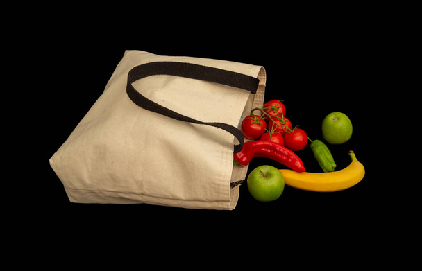 Verduras frescas y frutas en bolsa de tela aislada sobre fondo negro. - Foto, Imagen
