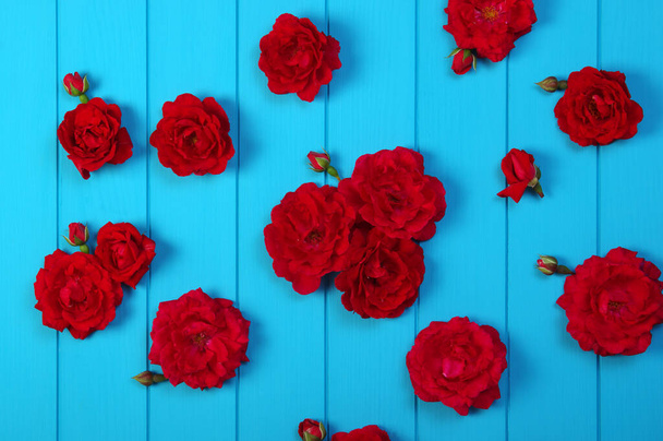 Flores de rosas rojas sobre tablones de madera pintados de azul.  - Foto, imagen