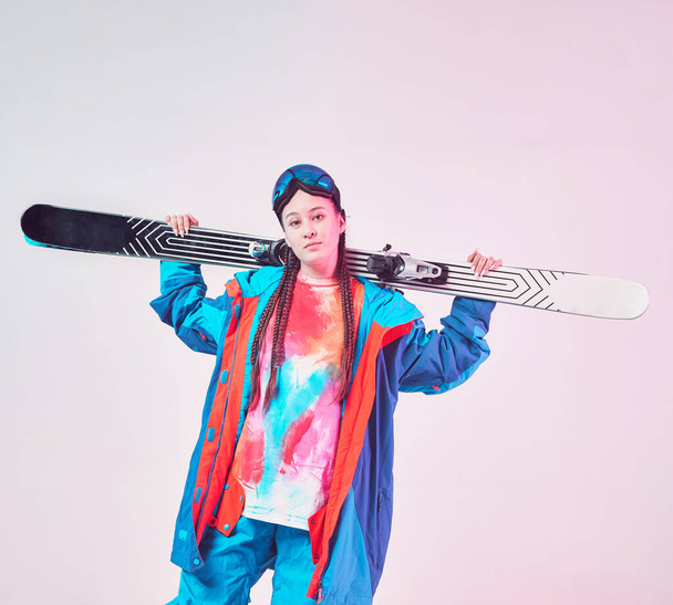 Sporty young girl skier in stylish winter sportswear and snowboarding goggles with ski posing in studio in neon light - Foto, Bild