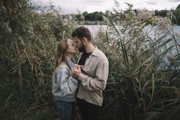 любящая пара стоит в тростнике на фоне озера вечером и общается - Фото, изображение