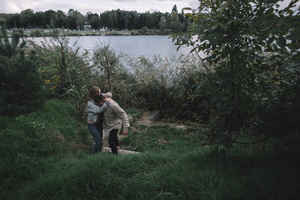 a loving couple stands in the reeds against the backdrop of a lake in the evening and communicates - Photo, Image