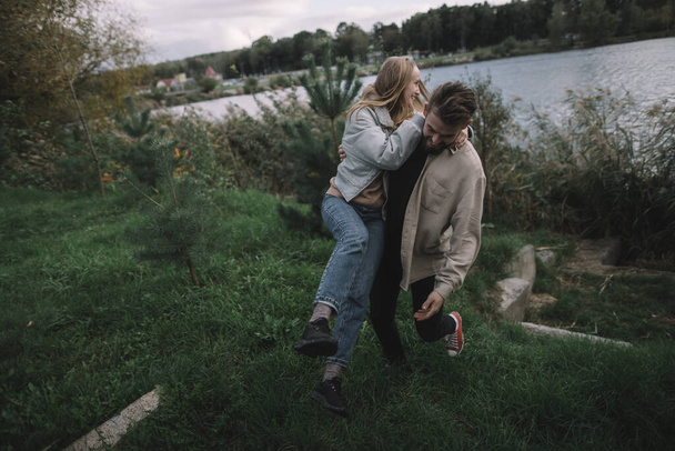 un couple aimant se tient dans les roseaux sur fond de lac le soir et communique - Photo, image