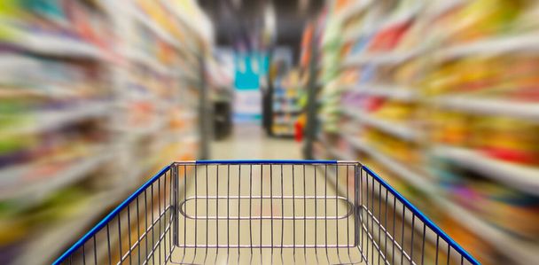 Supermarkt-Flur mit leerem blauen Einkaufswagen - Foto, Bild