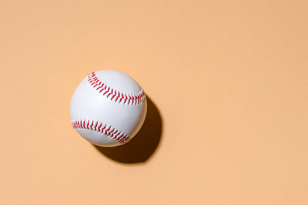Close up of baseball ball on camel color background. Online workout concept. - Foto, Bild