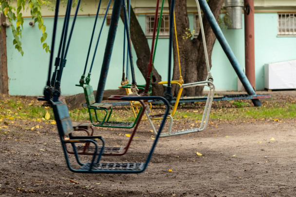 old swing for children abandoned in a park in autumn in ukraine in the city of dnipro - Photo, Image