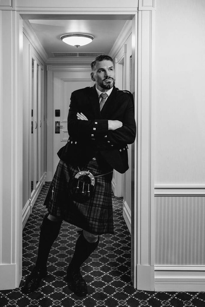 jóképű, érett, bátor, elegáns férfi (meleg) skót skót skót szoknyában, elegáns hotelszobában. Stílus, divat, életmód, kultúra, utazás, etnikai fogalom. - Fotó, kép