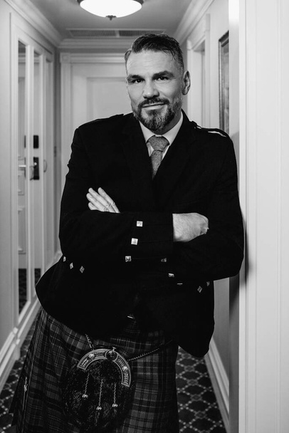 jóképű, érett, bátor, elegáns férfi (meleg) skót skót skót szoknyában, elegáns hotelszobában. Stílus, divat, életmód, kultúra, utazás, etnikai fogalom. - Fotó, kép