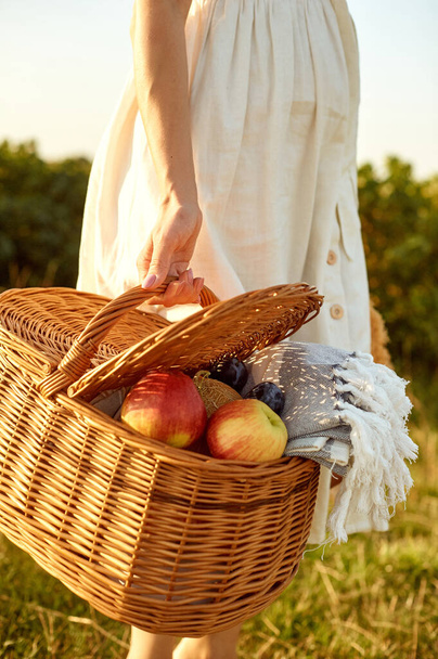 Wicker fruit basket in the hands of a woman. - Fotografie, Obrázek
