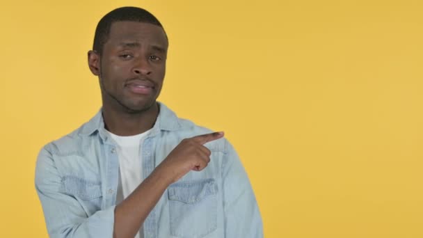 Homem Africano jovem apontando para o produto, fundo amarelo  - Filmagem, Vídeo