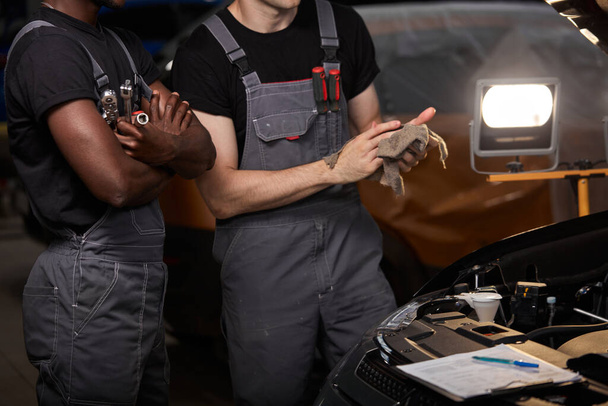 deux mécaniciens automobiles discuter des problèmes de réparation d'une voiture - Photo, image