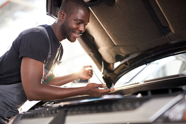 cheerful smiling afro man enjoy repairing cars hood - Fotografie, Obrázek