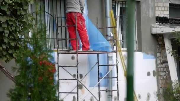 Рабочие изолируют квартиру, устанавливая изоляцию снаружи кирпичного дома - Кадры, видео