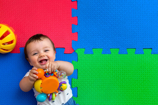 Funny baby playing on colorful eva rubber floor. Toddler having fun indoor his home. Top view. Copy space. - Photo, Image
