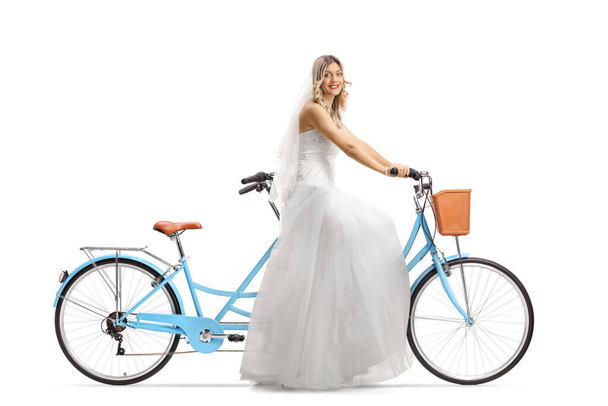 Full length shot of a beautiful bride riding a tandem bicycle and smiling at the camera isolated on white background - Fotó, kép