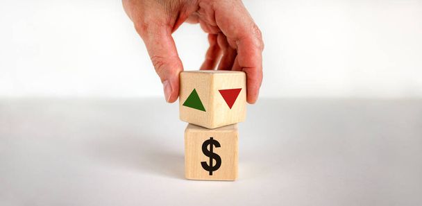 Male hand turns the wooden cubes changes the direction of an arrow symbolizing that the interest rates are going down or vice versa . Business concept. Beautiful white background, copy space. - Photo, image