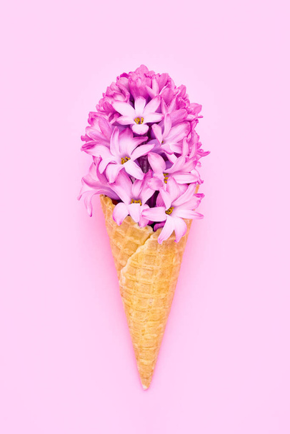 Waffle ice cream cone with pink hyacinth flower on pink background. Spring concept. Copy space, top view - Φωτογραφία, εικόνα