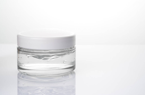 Crema facial en un frasco de vidrio sobre un fondo claro. - Foto, Imagen