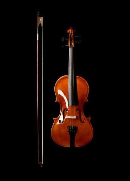 Brown wooden fiddle or violin, classic musical instrument, with bow next to it isolated over black background, flat lay top view from above - Valokuva, kuva