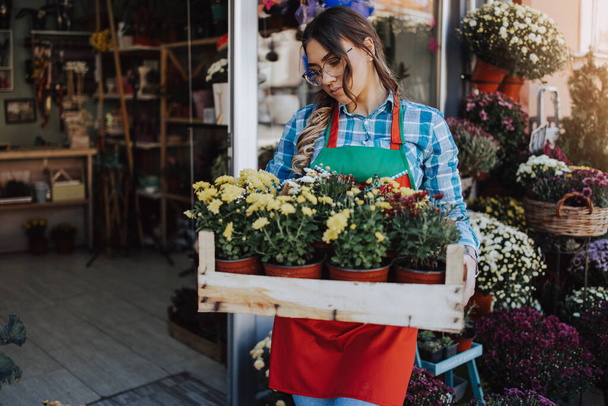 Young adult woman working in city street flower shop or florist. Small business concept. - 写真・画像
