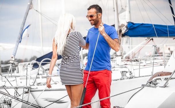 Latin man inviting sexy blonde woman on his yacht - Foto, afbeelding
