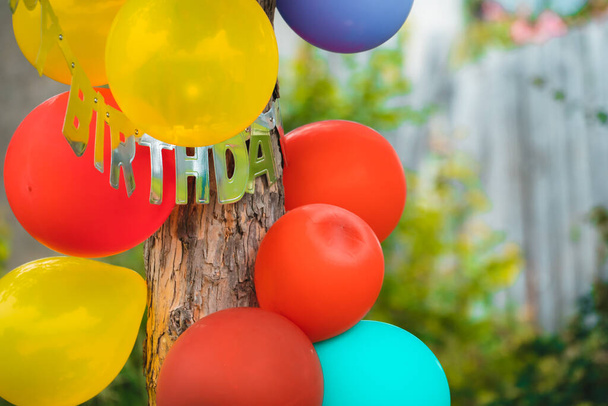 Party-Luftballons hängen an einer Kiefer im Garten, in dem gefeiert wird - Foto, Bild