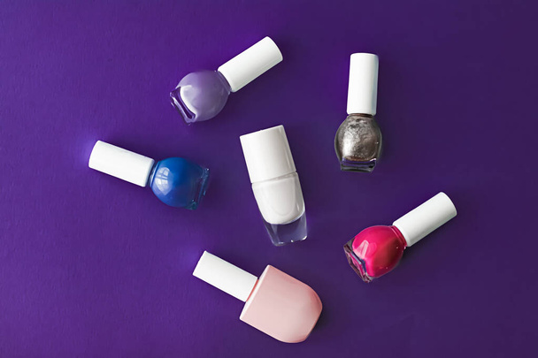 Nail polish bottles on dark purple background, beauty brand - Photo, Image