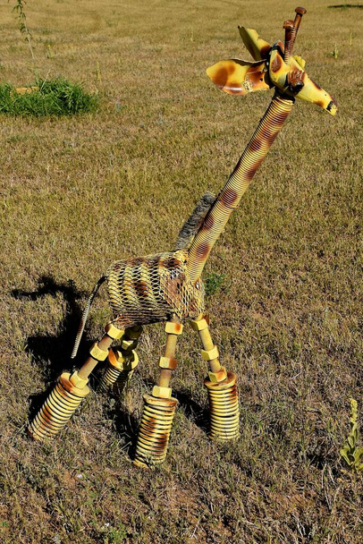 Una jirafa esculpida de metal hecha de piezas de metal desechadas y pintada en aerosol. - Foto, Imagen