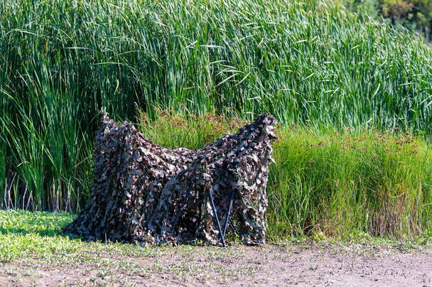 Камуфляжная палатка для засады в тростнике у реки - Фото, изображение