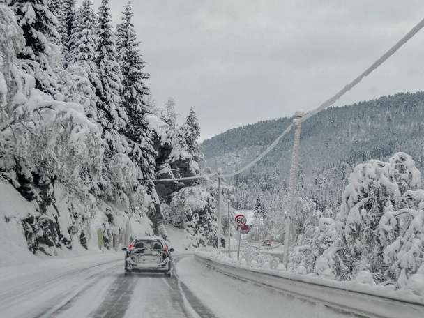 Driving through snowy white road and landscape in Norway. Car in front. - 写真・画像