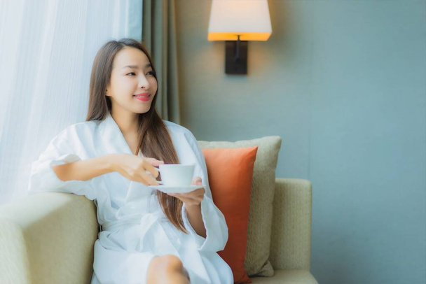 Porträt schöne junge asiatische Frau mit Kaffeetasse auf Sofa im Wohnbereich Innenraum - Foto, Bild