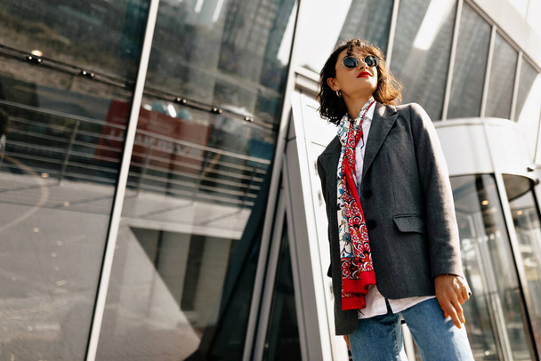 Stylish pretty woman in casual outfit standing against business centre in sunny day. High quality photo - Fotografie, Obrázek