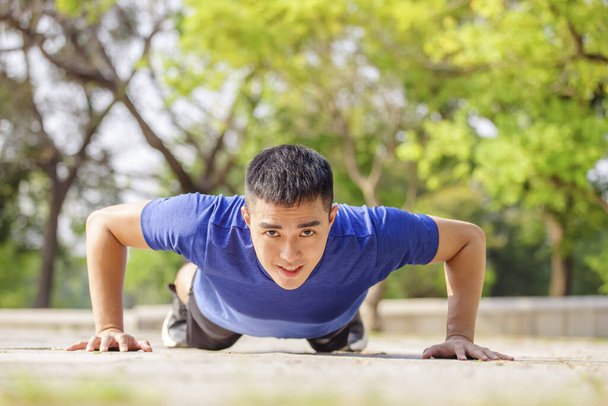 young handsome man doing push up exercise in the park - Photo, Image